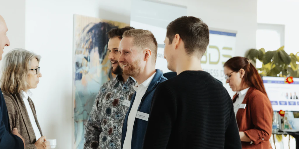 Teilnehmende des CustomerOne Kundentag 2024 sprechen miteinander
