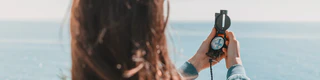 Frau hält Kompass in den Händen und schaut auf Meer