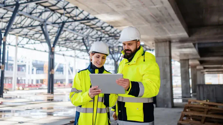 Zwei Personen auf Baustelle schauen auf Tabletscreen